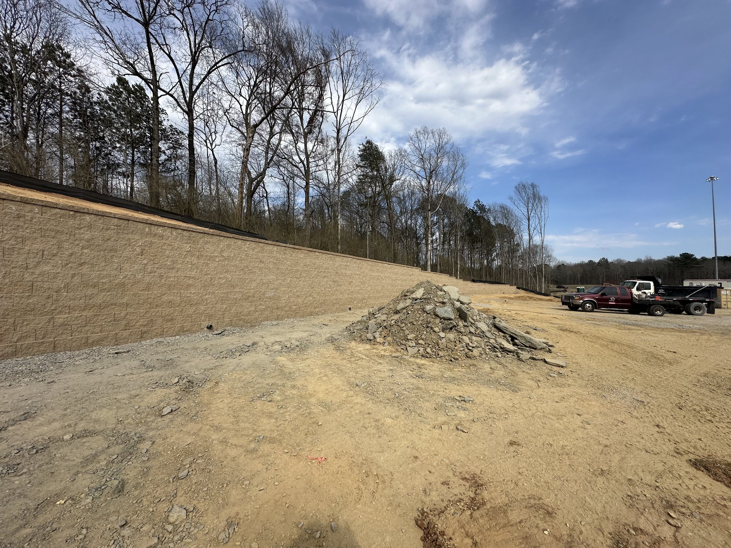Commercial retaining wall construction with work trucks staged nearby