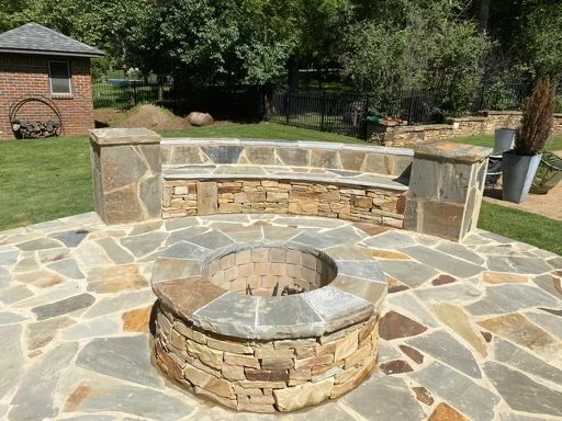 Overhead view of a stone fire pit and curved seating wall on a flagstone patio