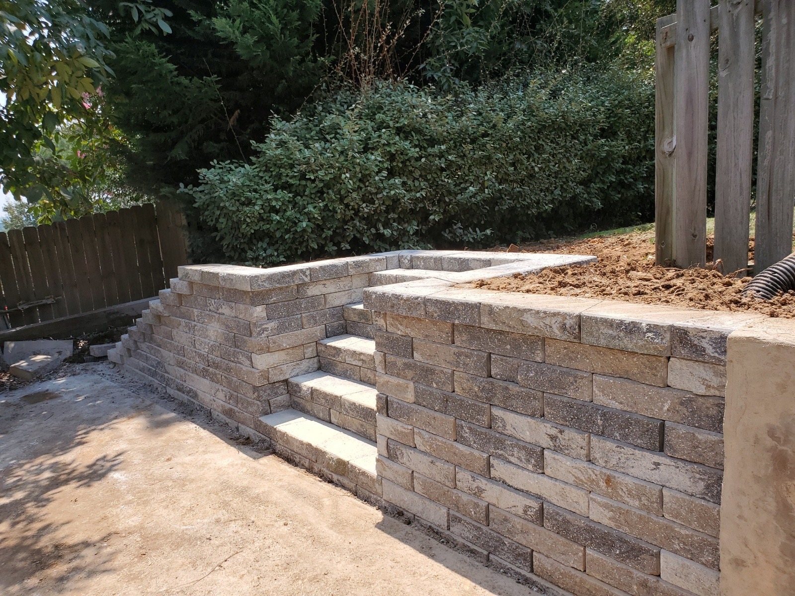Segmental block retaining wall with integrated stone steps leading to a patio
