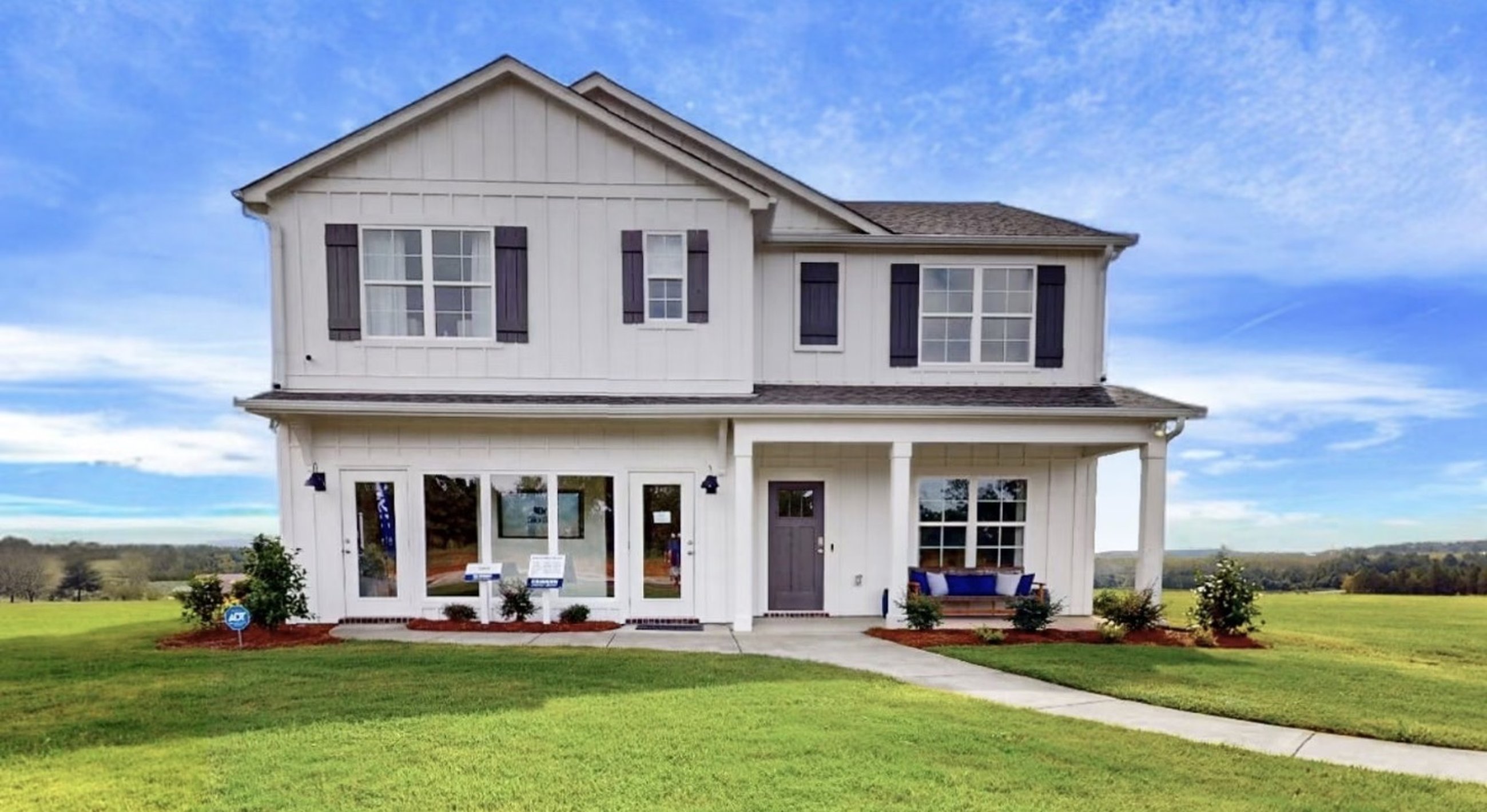 New construction home with a wraparound front porch, fresh sod, and landscaped beds