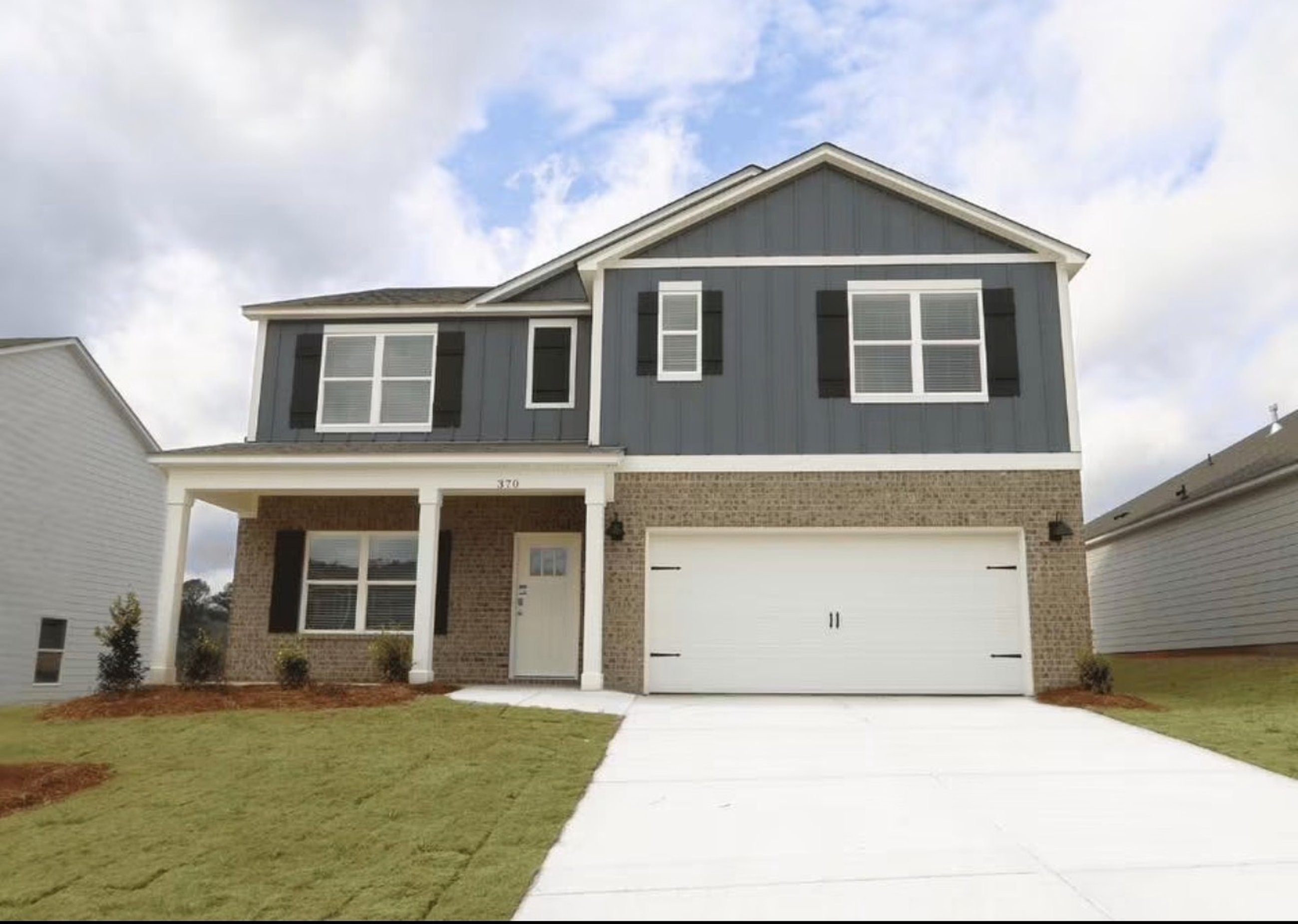 Newly built two-story home with a freshly installed lawn and landscaped front beds